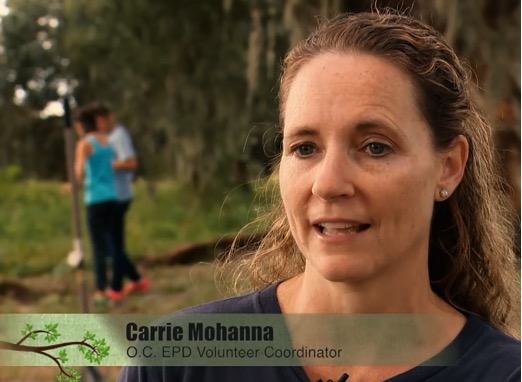 Volunteer coordinator Carrie Mohana standing in a wooded area