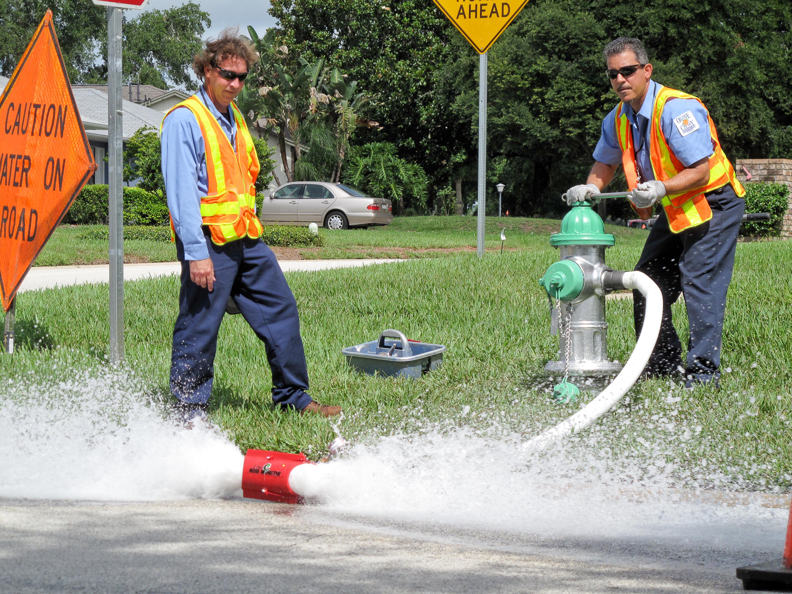 Two utility workers flushing out a fire hydrant