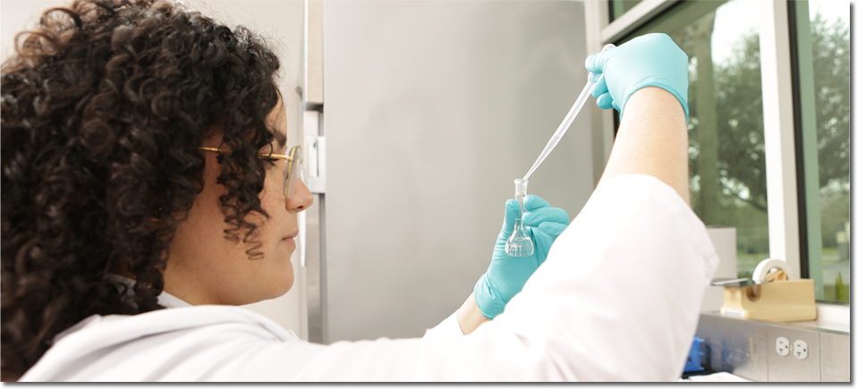 A lab technician adding drops of sample water into a test tube