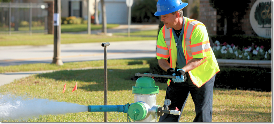 Photo of a utility worker opening up a fire hydrant with a wrench