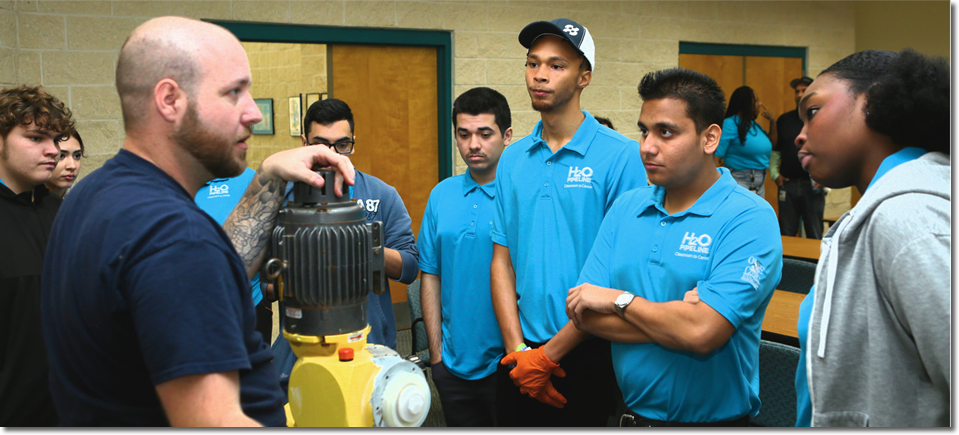 Photo of a teacher and multiple students demonstrating a water pump